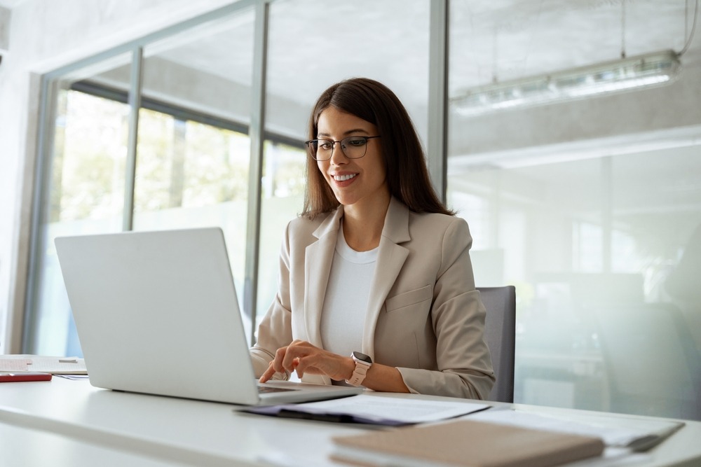 Smiling,Middle,Aged,Business,Woman,Using,Laptop,At,Work,In