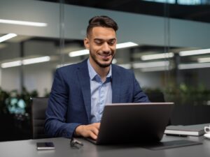 Smiling,Young,Middle,Eastern,Businessman,Sitting,At,Worktable,At,Modern