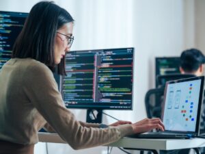 Asian,Software,Developers,Working,On,Multiple,Screens,Displaying,Code,And